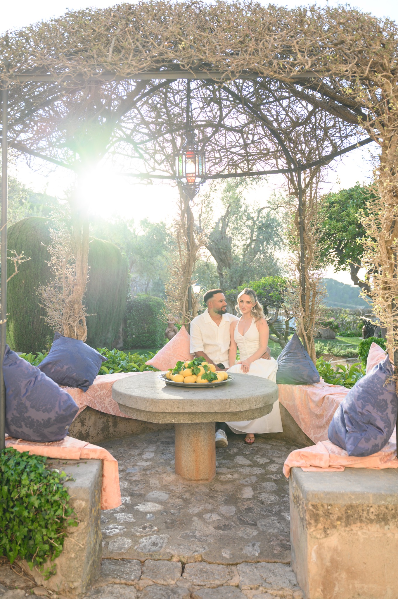 Laura and Andrés seated together beneath a vine-covered garden structure